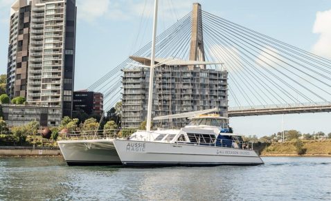 Luxury charter yacht sailing beneath Sydney's iconic Anzac Bridge.
